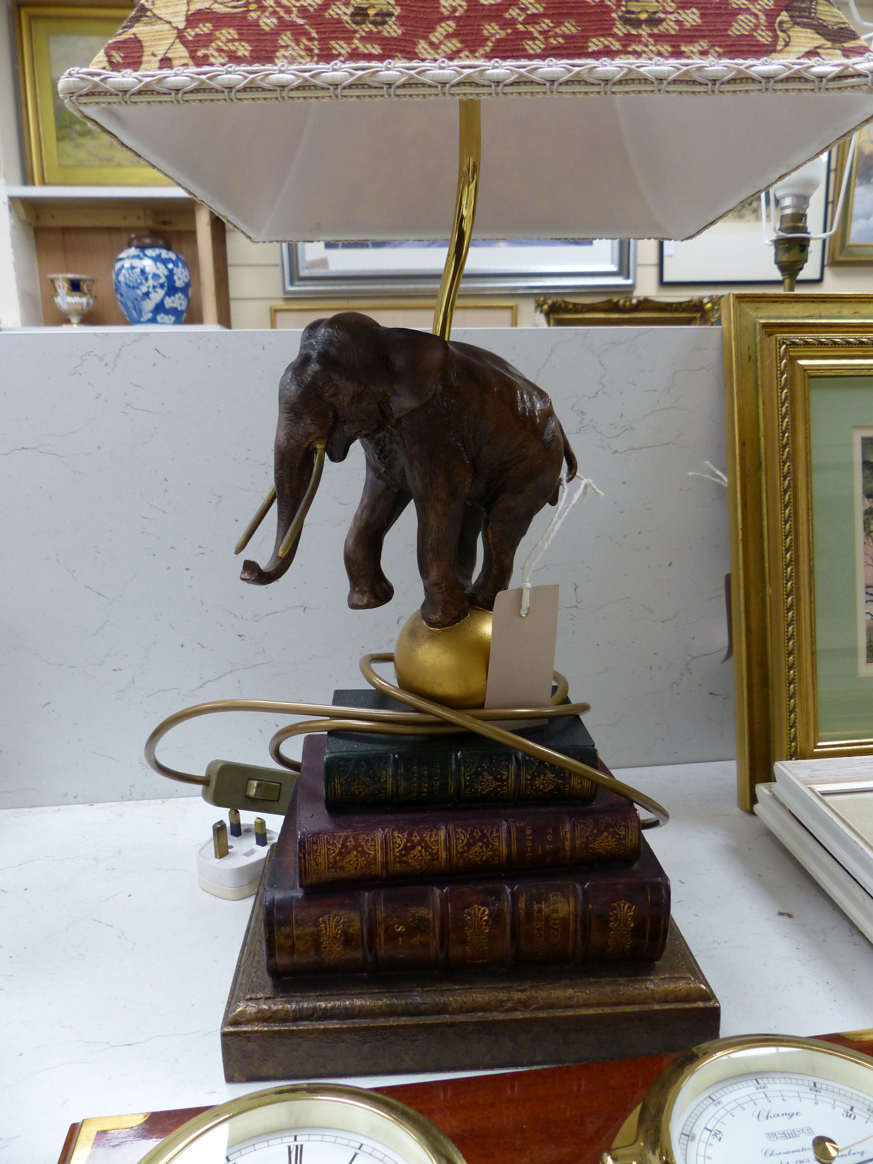 A Wempe wall-mounted ship's style clock/barometer and an 'elephant on books' table lamp